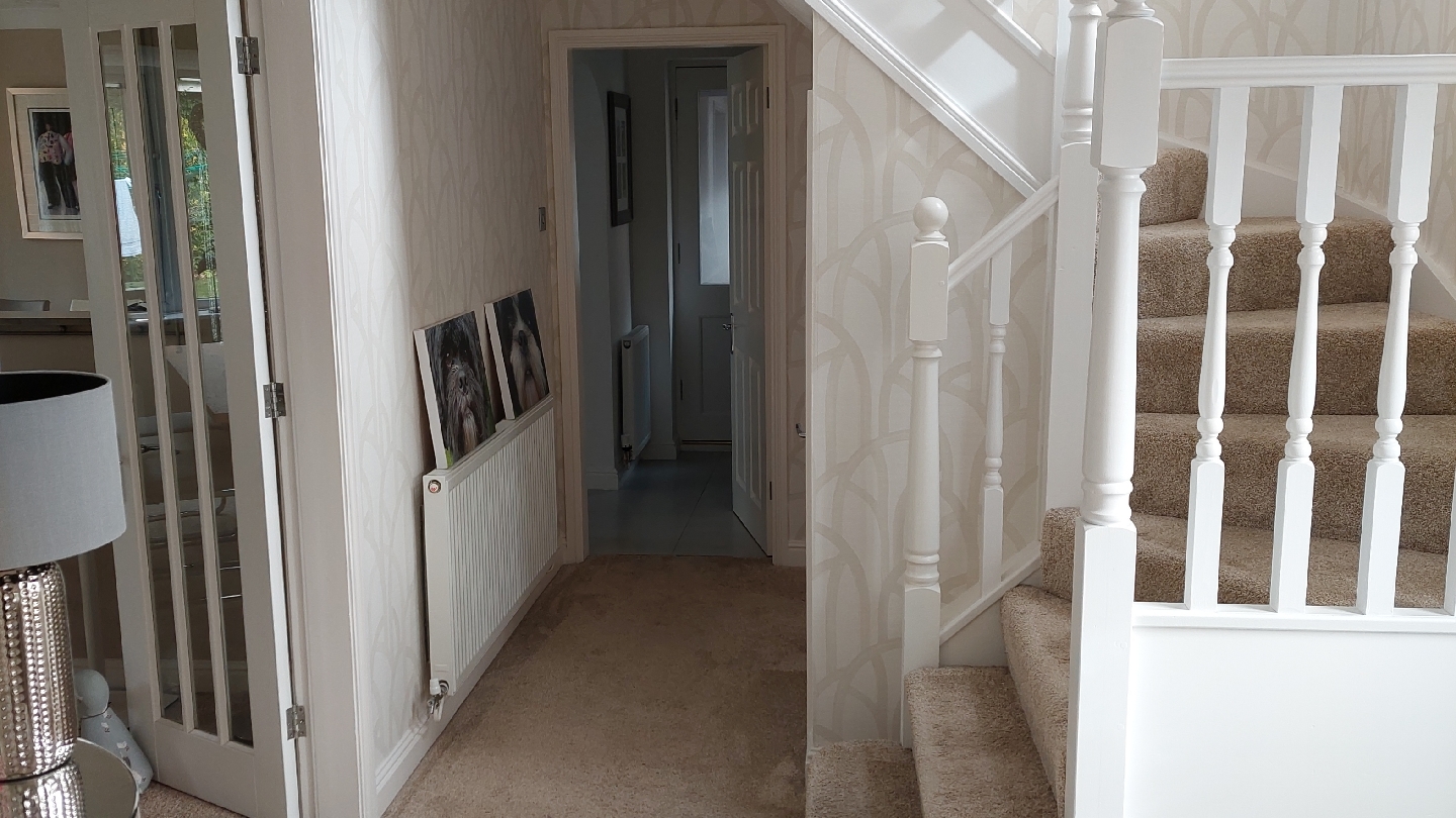 Hallway and staircase with white spindles and patterned wallpaper