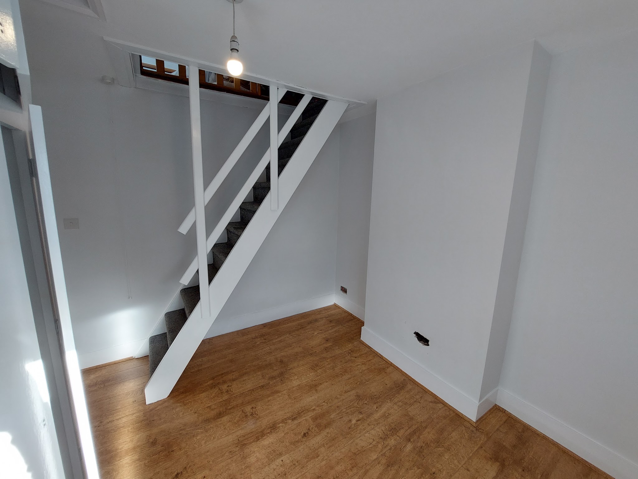 White room with open staircase and wood-effect floor
